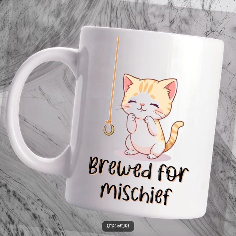 Funny mug showing a tiny, curious cat playfully batting at a dangling thread attached to a crochet hook with intense focus.