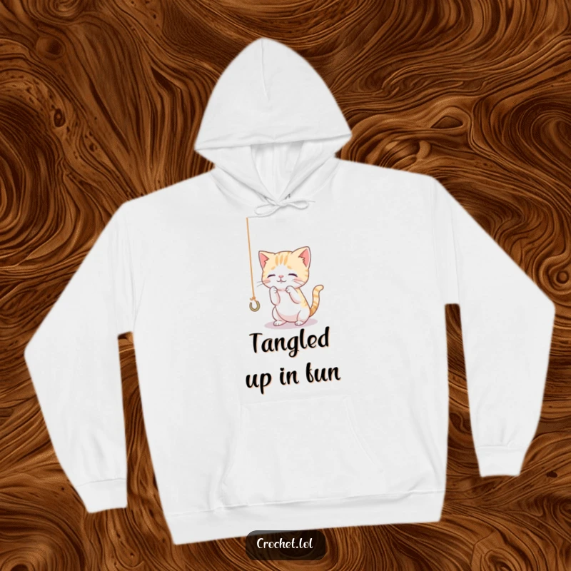 Funny hoodie featuring a tiny, curious cat playing with a dangling thread and hook, designed for ultimate comfort and feline fun.